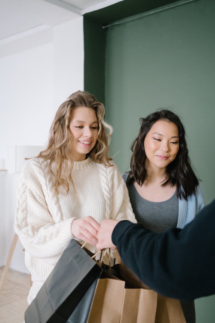 Two women receiving shopping bags, engaging in indoor retail environment.
